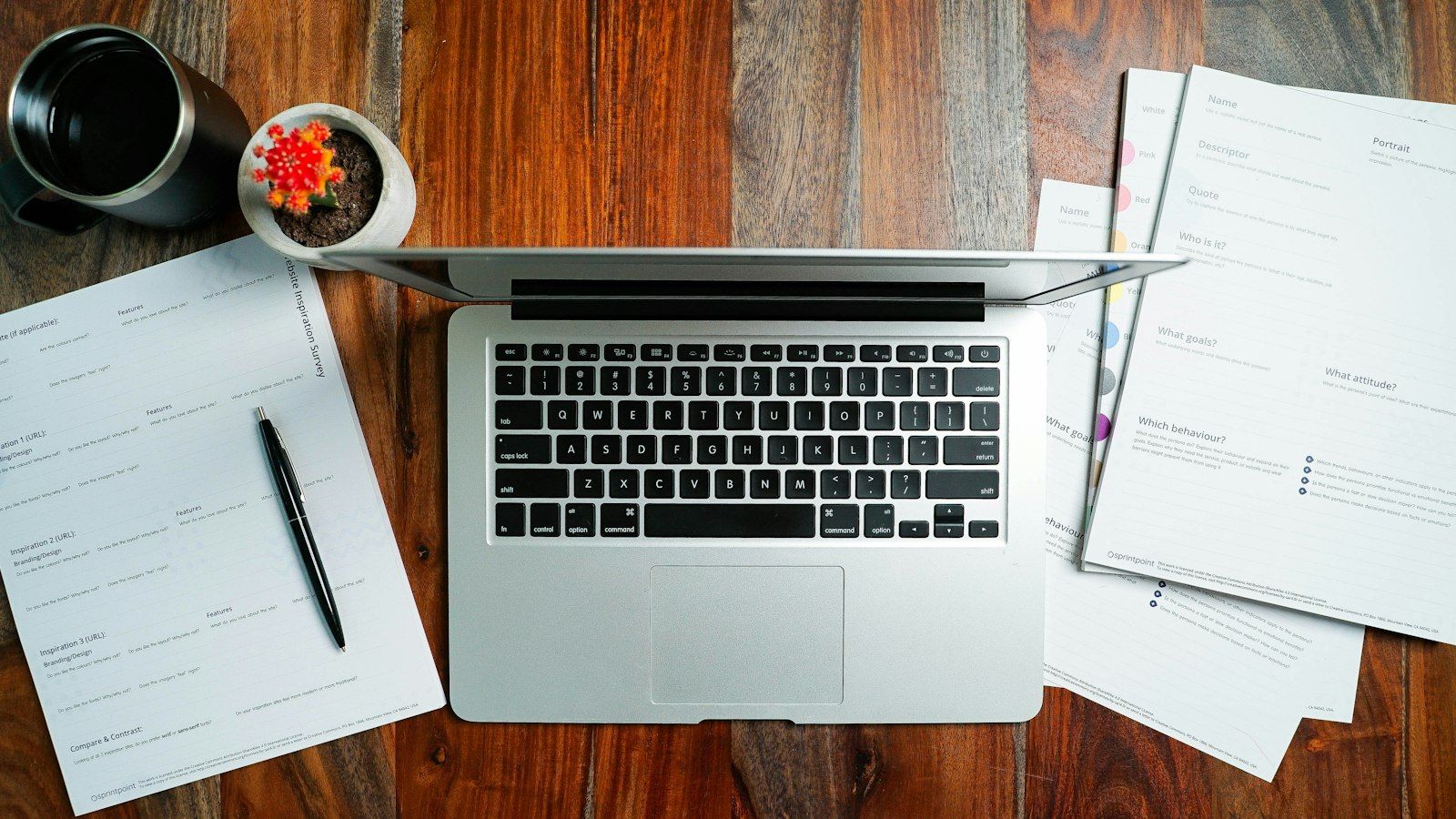 A laptop and loose papers on a wooden desk, ready for a file review