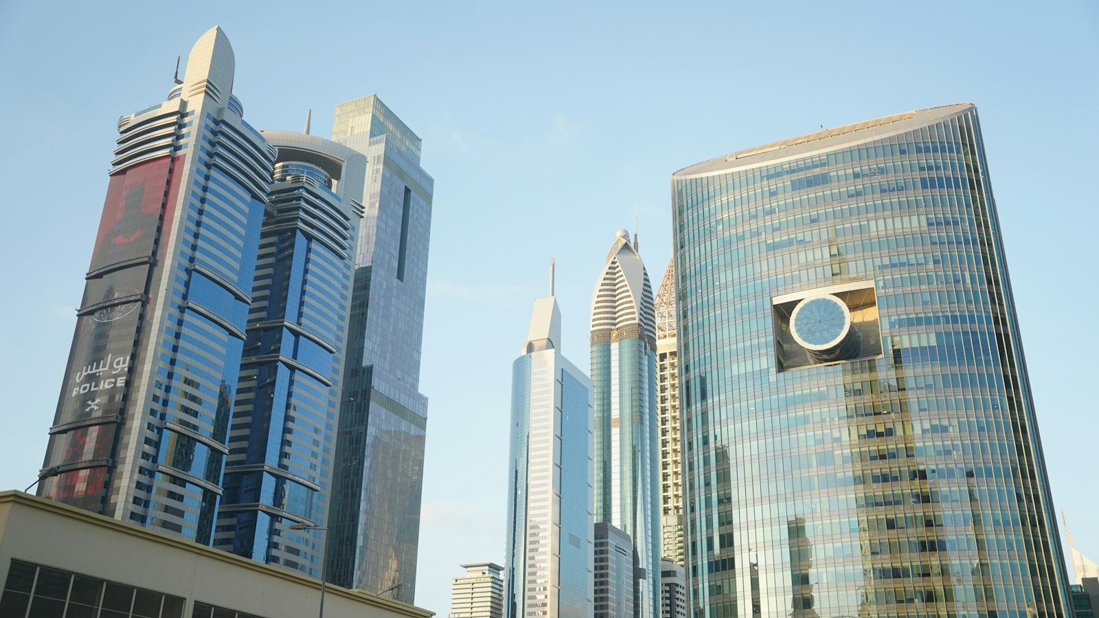 Glass office towers rising into a clear blue sky in Dubai