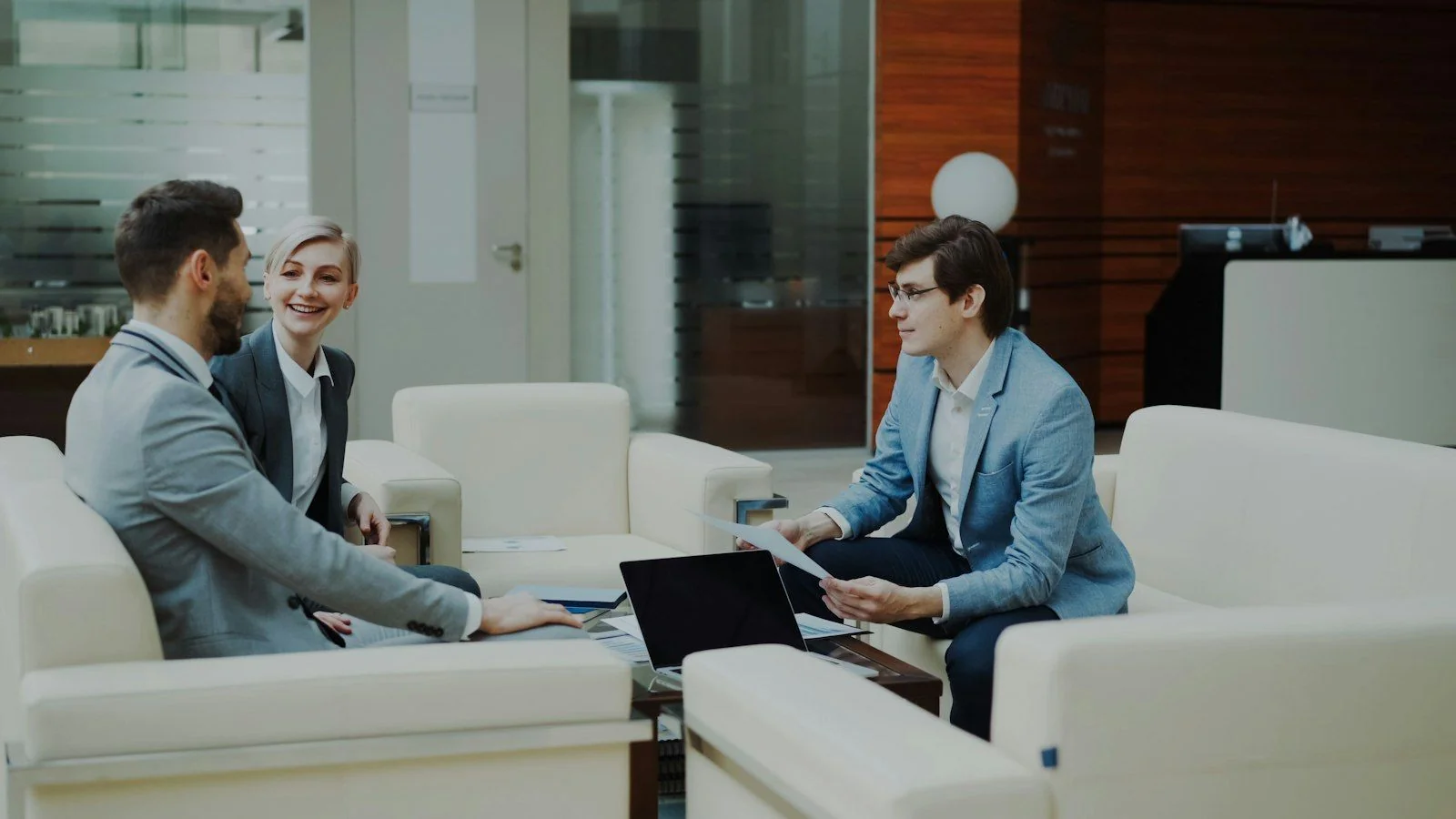 Three advisers talking through a plan on a sofa in a modern office
